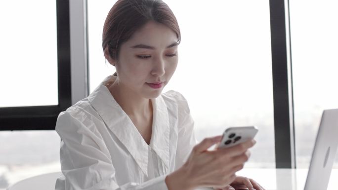 年轻快乐迷人美丽的亚洲女性员工在手机上谈笑风生
