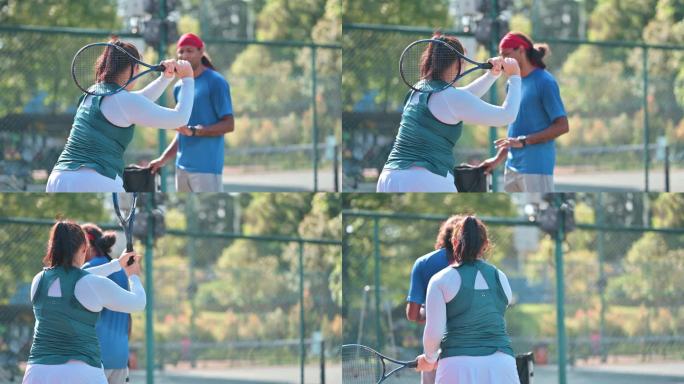 亚洲中国中年女子周末上午在网球场向教练学习网球
