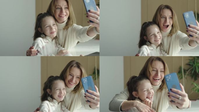 年轻快乐的母亲和可爱的女儿使用智能手机进行视频聊天