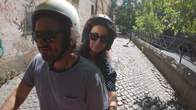 意大利罗马，一对年轻夫妇在骑红色摩托车时录制视频