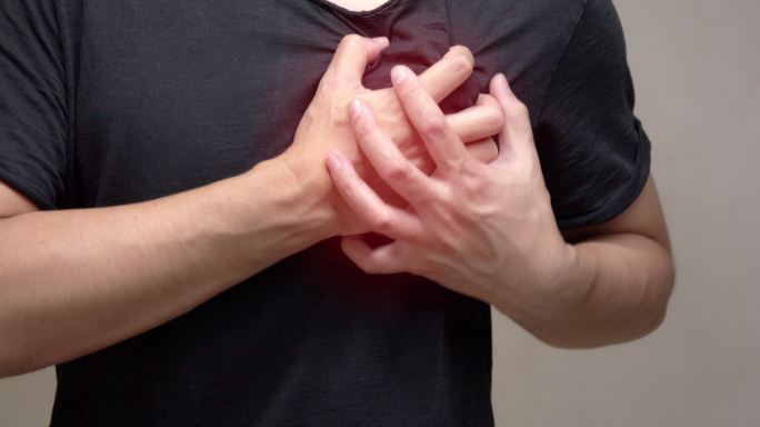 身穿黑色衬衫的亚洲男子感到心脏疼痛。心脏病发作，健康护理理念。