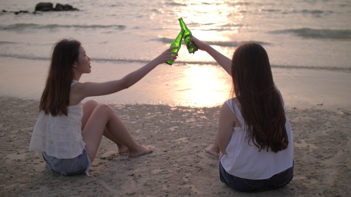 一群女人在日落和饮酒的海滩上快乐和聚会