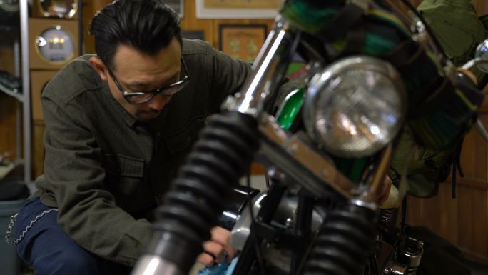 一名男子在车库里打磨和维护他的定制摩托车