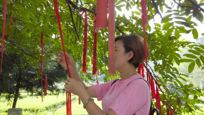 女人在树上挂红布祈福