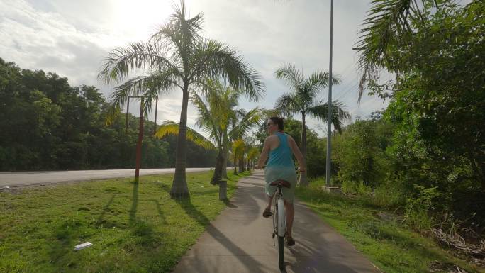 妇女骑自行车沿着丛林小路，路边