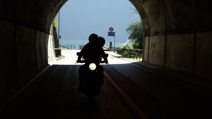一对夫妇骑着摩托车在湖边的路上
