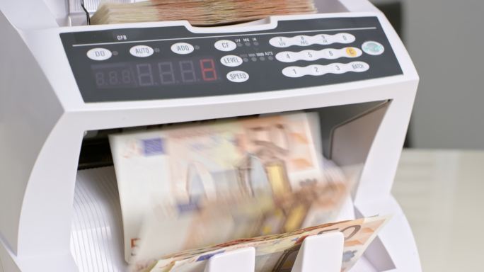 女性手把50欧元钞票喂入钱柜，然后在里面乱晃