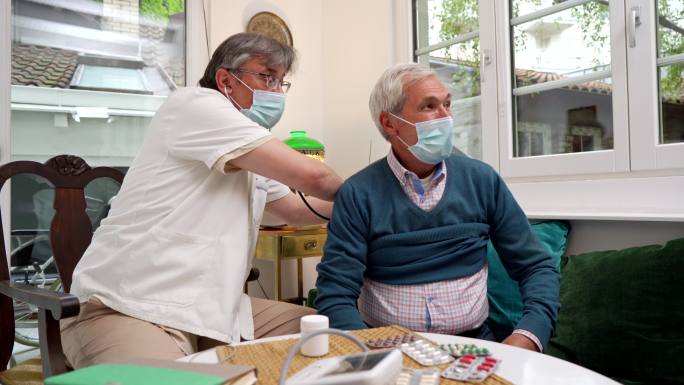 疗养院的肺科医生用听诊器检查一位老年患者的肺活量