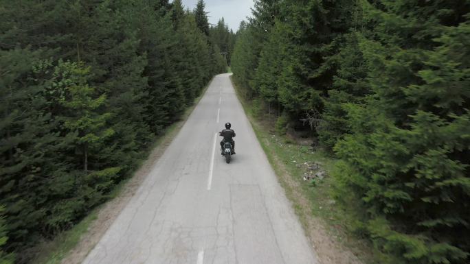 男子骑摩托车上路摩托车潇洒骑行松树森林公