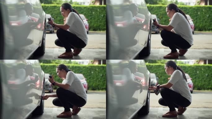 亚洲中年女性使用智能手机显示屏检查汽车轮胎气压，出行前进行汽车检查