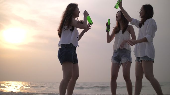 一群女人在日落和饮酒的海滩上快乐和聚会