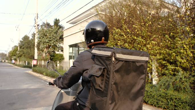 一名年轻的亚洲男子骑着一辆摩托车被要求送到客户家中。