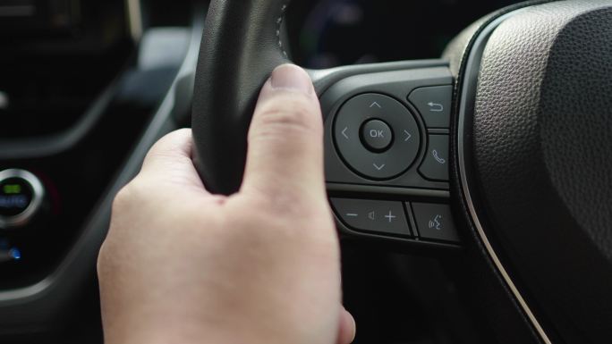 驾驶时拇指按下汽车方向盘上的多媒体呼叫控制器按钮
