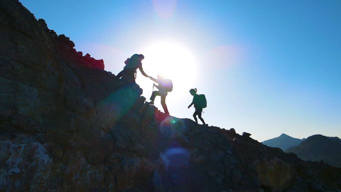 团队协作手拉手登山户外探险攀登顶峰旅行者