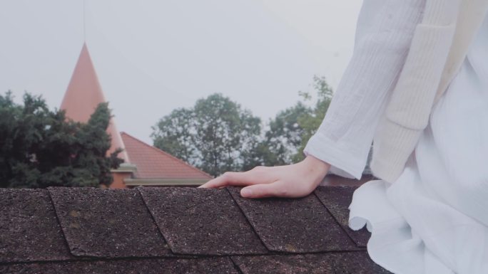 一姑娘坐在屋檐上，手扶着瓦片 房顶休闲