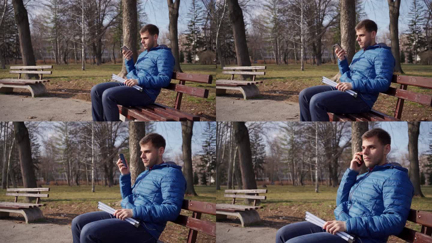 视障男子坐在公园长椅上，使用手机