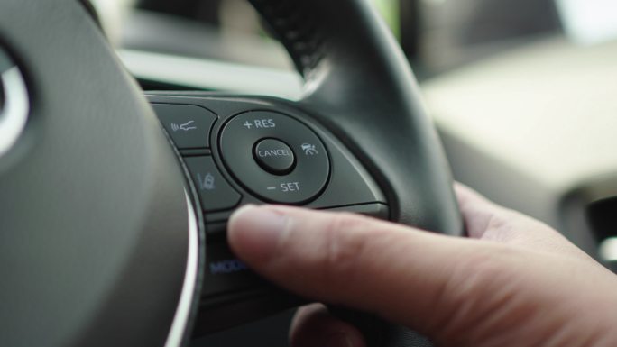驾驶时拇指按下汽车方向盘上的多媒体控制器按钮