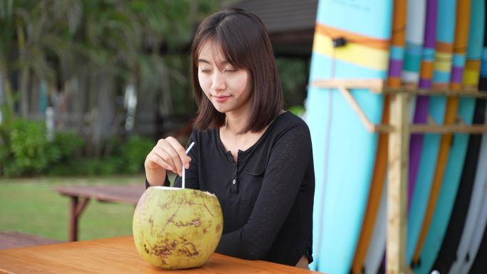 女孩在海边喝椰子水看日落海边看海游玩