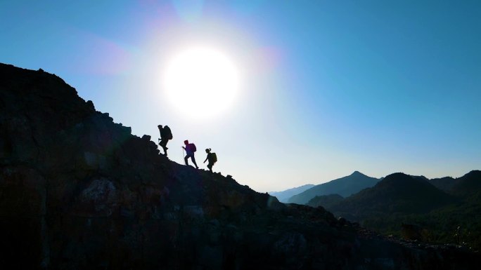 团队登山剪影团结奋进人物逆光走向山顶攀登
