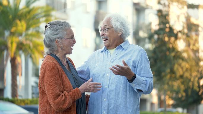 多种族的老年夫妇在楼外谈笑风生