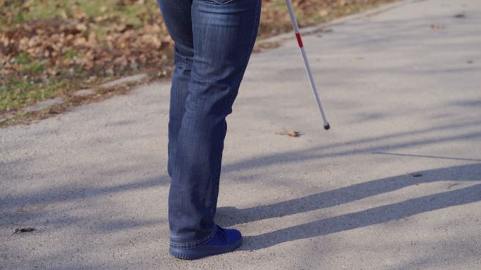 无法辨认的盲人用手杖在公园里行走