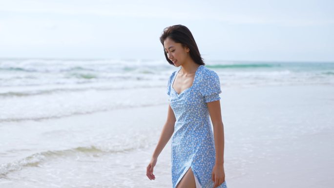 女孩开心的走在沙滩上看海微笑