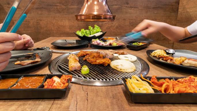 时间流逝：亚洲人在韩国餐厅烧烤烧烤。食品概念