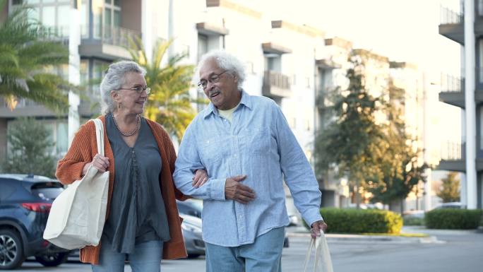 老年夫妇交谈，带着可重复使用的袋子在城市里散步