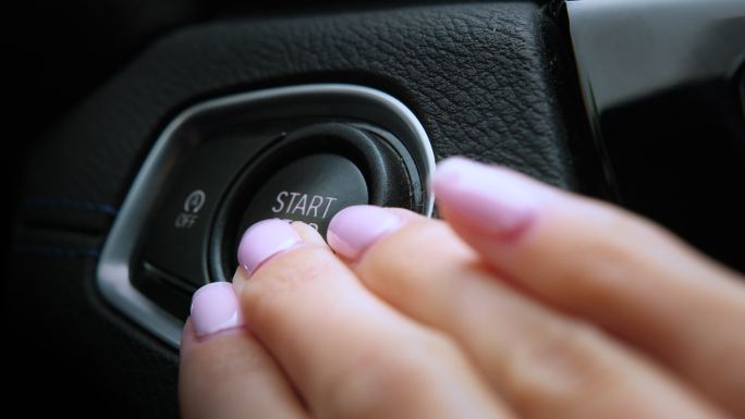 女性手指按下“启动发动机”按钮。现代汽车内饰