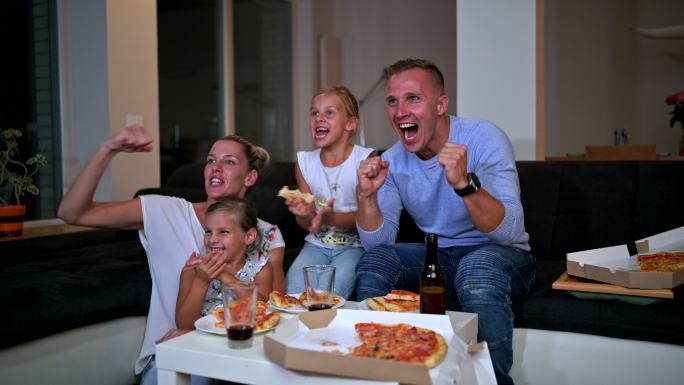 高加索家庭坐在沙发上吃披萨看电视
