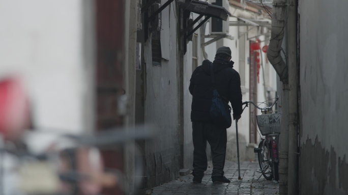 拄拐杖老人走在巷子里，行走不便的老人