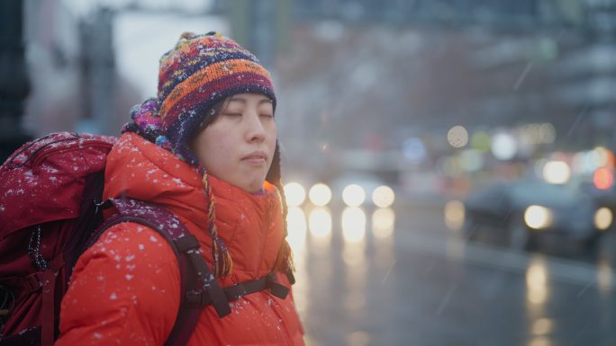 冬天在城市红绿灯前等待的年轻女性旅行者