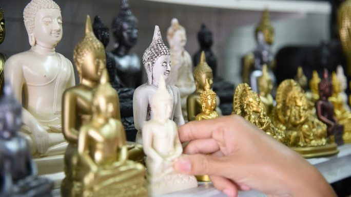 泰国一名女游客在纪念品商店挑选佛像。