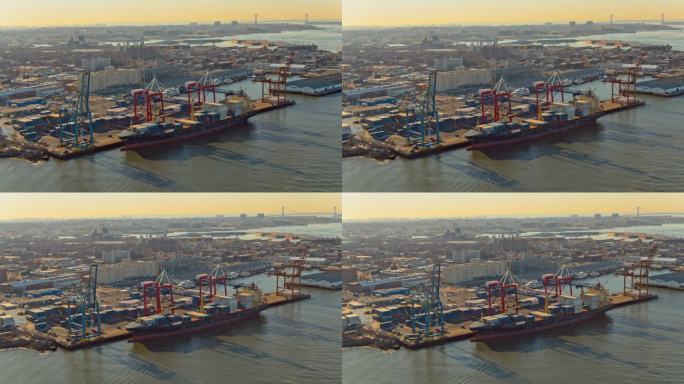 日落时分，工业集装箱船正在纽约布鲁克林东河的商业码头装货。无人机通过电影般的全景轨道摄像机运动拍摄视