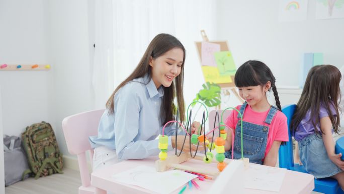 亚洲美丽的年轻女教师在学校给孩子上课。吸引人的女教师大师在幼儿园的课堂上用有趣的活动向孩子们讲解和教