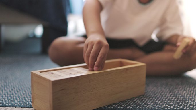 一个亚洲小男孩在家里的卧室里玩木块地板游戏。