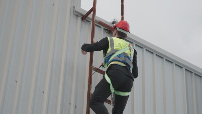 工程人员或技术人员或承包商穿着安全制服，爬上工厂屋顶，检查项目进度，并在建筑屋顶上安装太阳能发电厂的