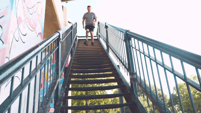 自信的男性适应性运动员跑下楼梯