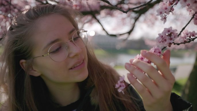 少女在美丽的樱花树上欣赏春天的花朵