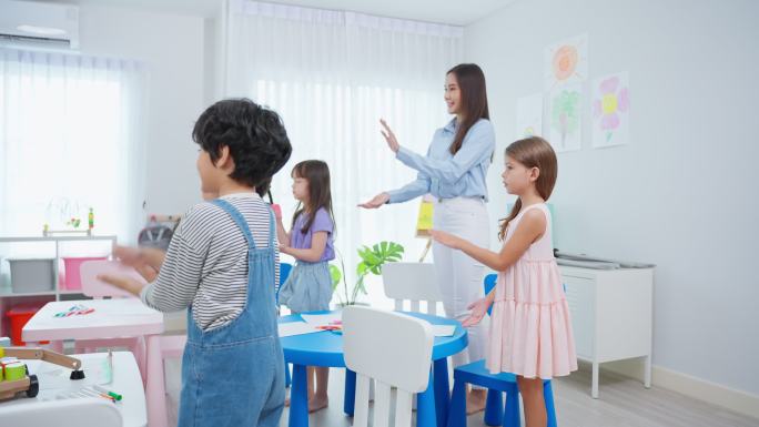 亚洲美丽的年轻女教师在学校给孩子上课。吸引人的女教师大师在幼儿园的课堂上用有趣的活动向孩子们讲解和教