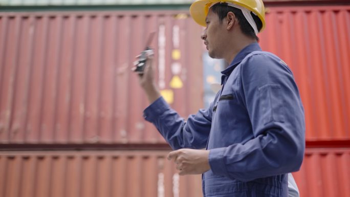 专业亚洲经理与工程师或技术人员讨论集装箱维护系统，并根据运输计划控制叉车提升集装箱卡车上的货物。物流