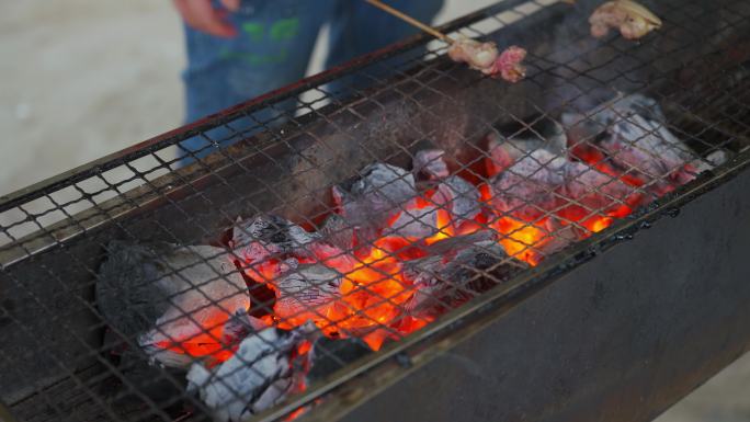 一群人围在火炭炉前烧烤，烧烤各种食材