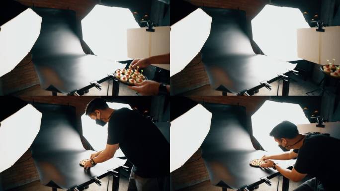 摄影师在摄影棚的黑色布景上摆放食物