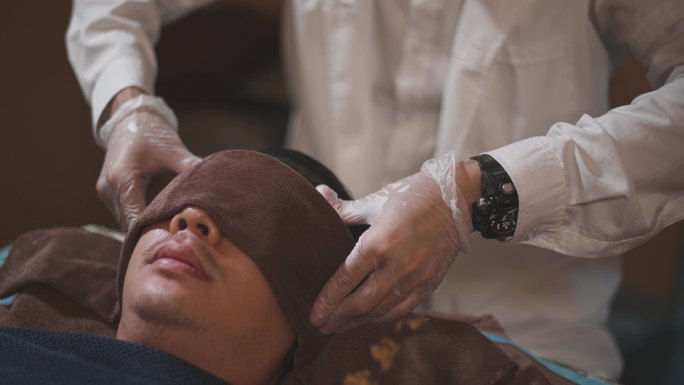 亚洲男性按摩师按压患者头部穴位缓解压力指压