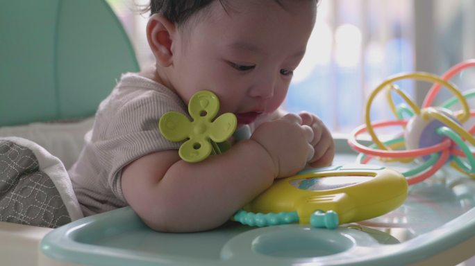 快乐的亚洲男婴玩耍和咬孩子的玩具。