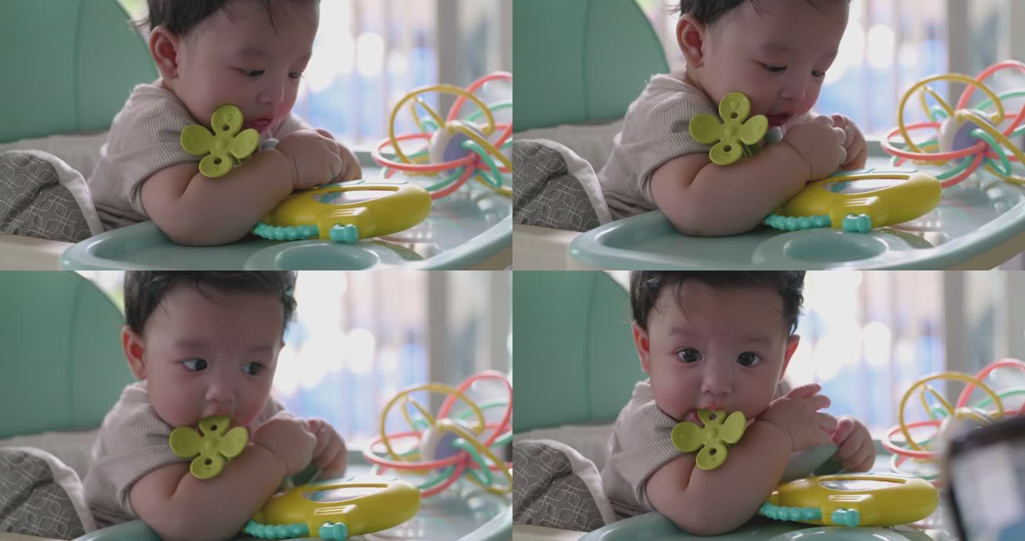 快乐的亚洲男婴玩耍和咬孩子的玩具。
