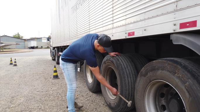 巴西卡车司机检查他的半卡车轮胎。