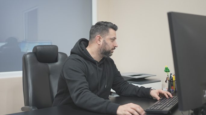 英俊的男性上班族在电脑上工作时接听电话