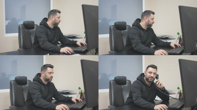 英俊的男性上班族在电脑上工作时接听电话