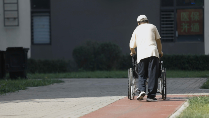 小区社区老人推着轮椅的背影腿脚不好